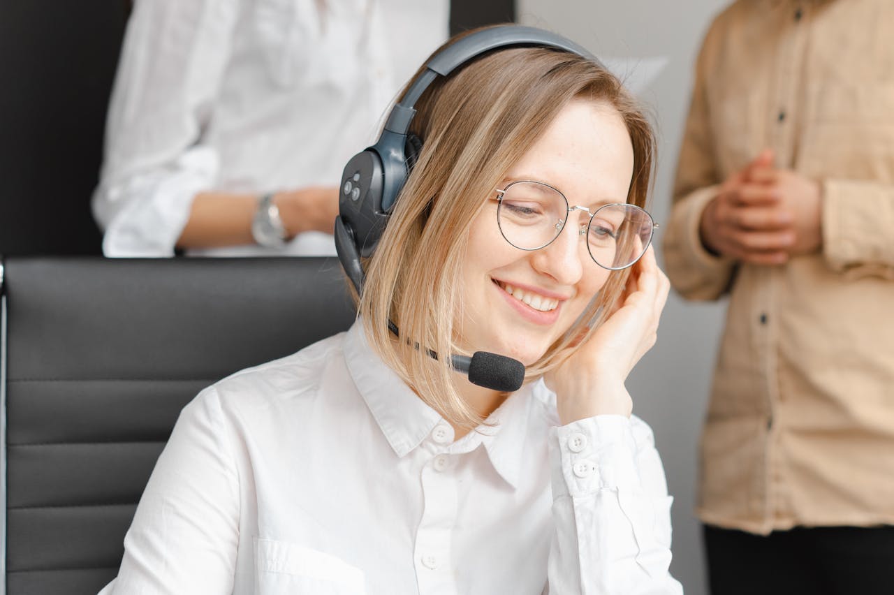 A cheerful woman working at a call center, wearing a headset and glasses, providing excellent customer support.